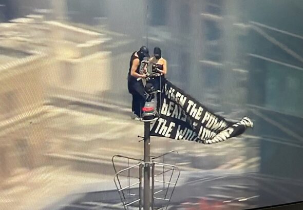 Two people climb to the top of Empire State Building with massive banner
